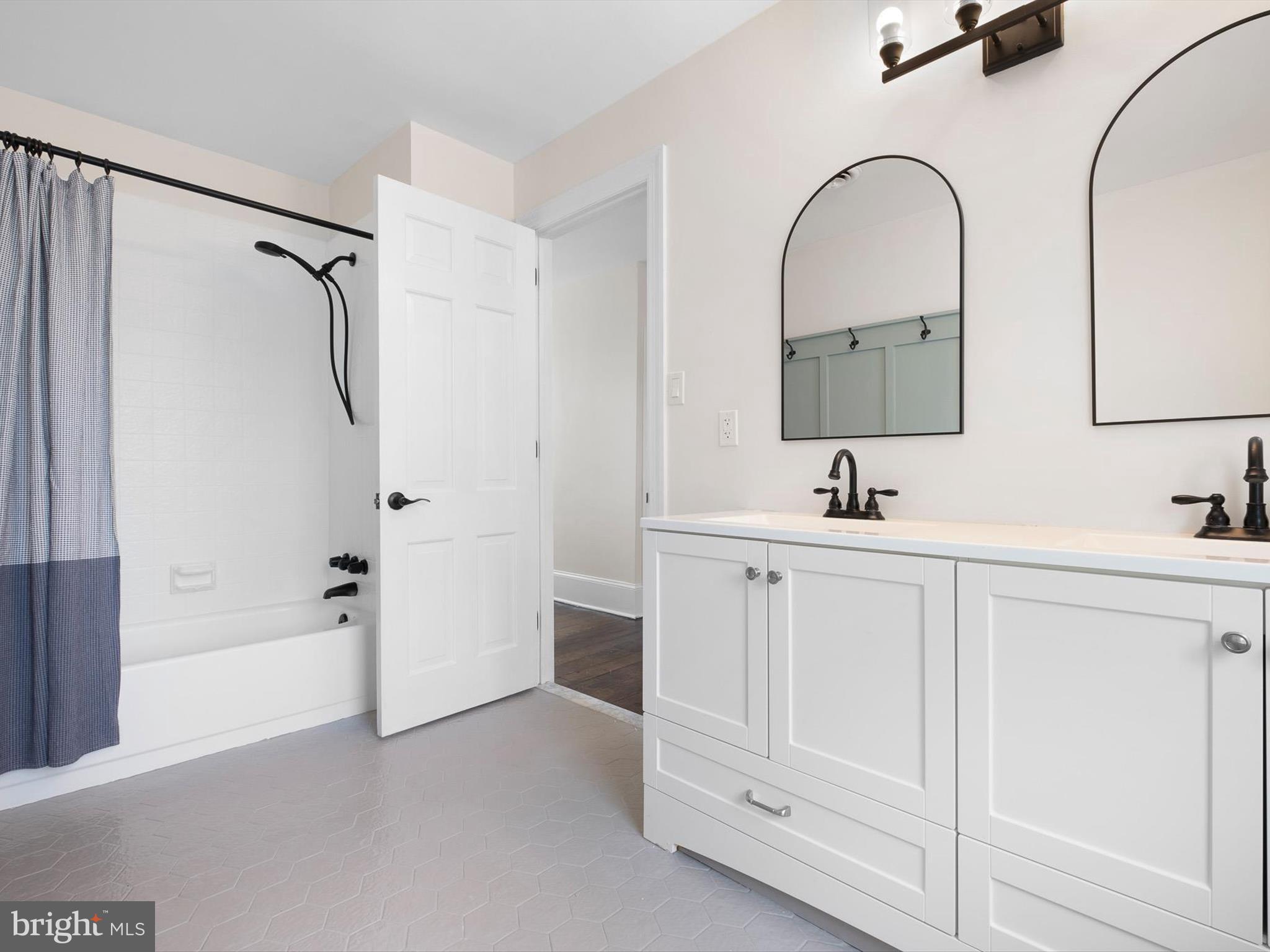5961 Limestone Road Hockessin, DE 19707 - Photo 24 of 40 a bathroom with a double vanity sink a mirror a bathtub and shower