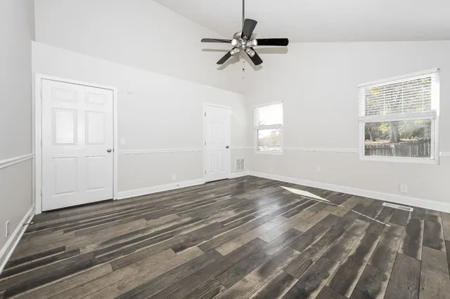 a view of empty room with wooden floor and fan