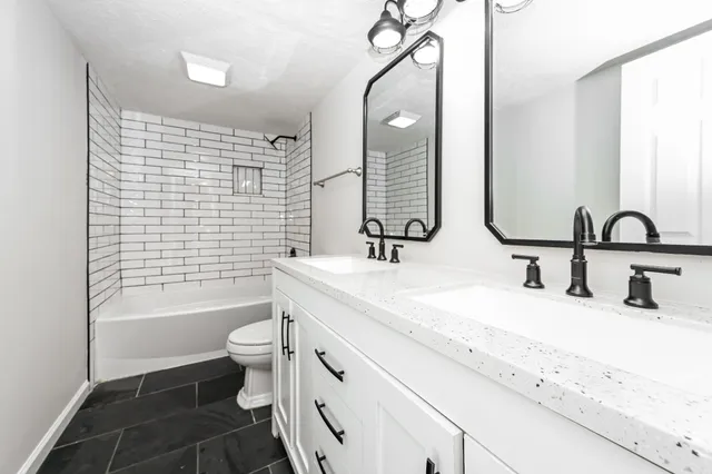 a bathroom with a double vanity sink toilet mirror and bathtub