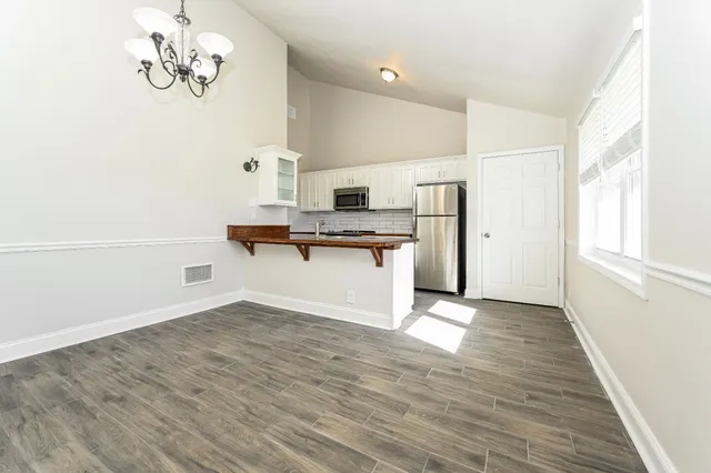 a view of a kitchen with wooden floor and a refrigerator