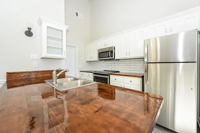 a kitchen with stainless steel appliances granite countertop a refrigerator a stove a sink a dining table and chairs