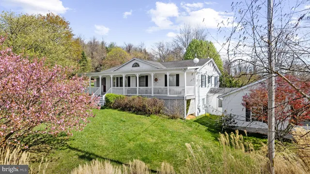 a view of a house with a big yard plants and large trees