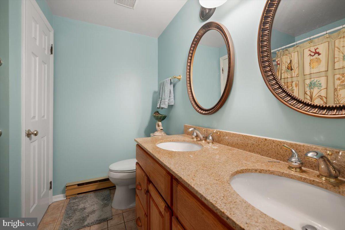 1049 Laurel Grove Road Winchester, VA 22602 - Photo 22 of 42 a bathroom with a granite countertop toilet a sink and a mirror