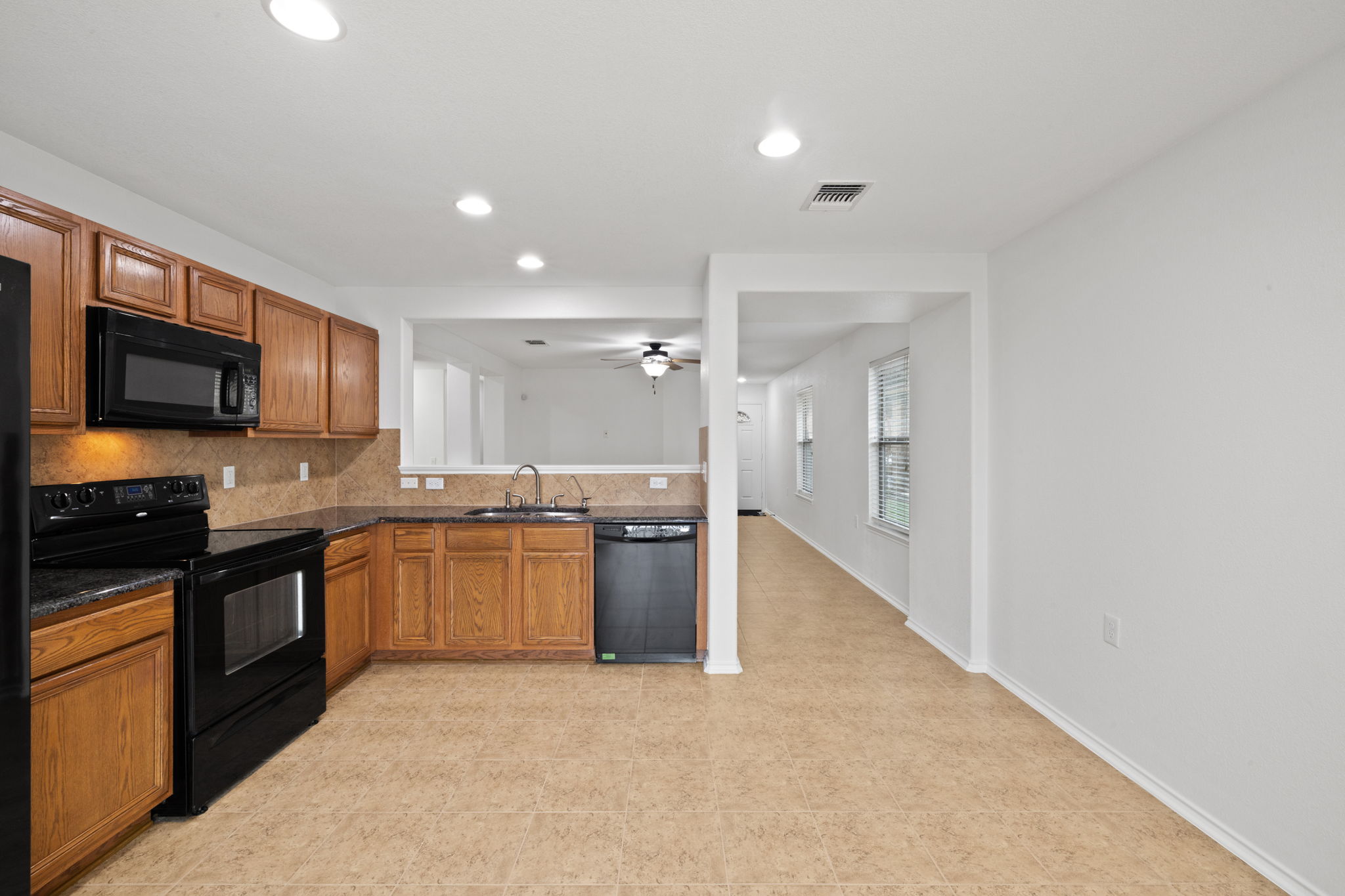 8825 Stambourne Street Austin, TX 78747 - Photo 12 of 37 a large kitchen with granite countertop a stove top oven sink and cabinets