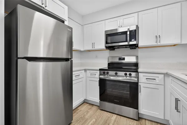 a kitchen with stainless steel appliances white cabinets white stove a microwave and a refrigerator