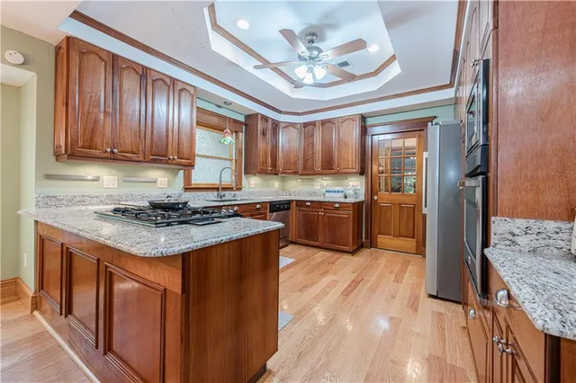 a kitchen with stainless steel appliances granite countertop wooden cabinets a refrigerator and a stove top oven
