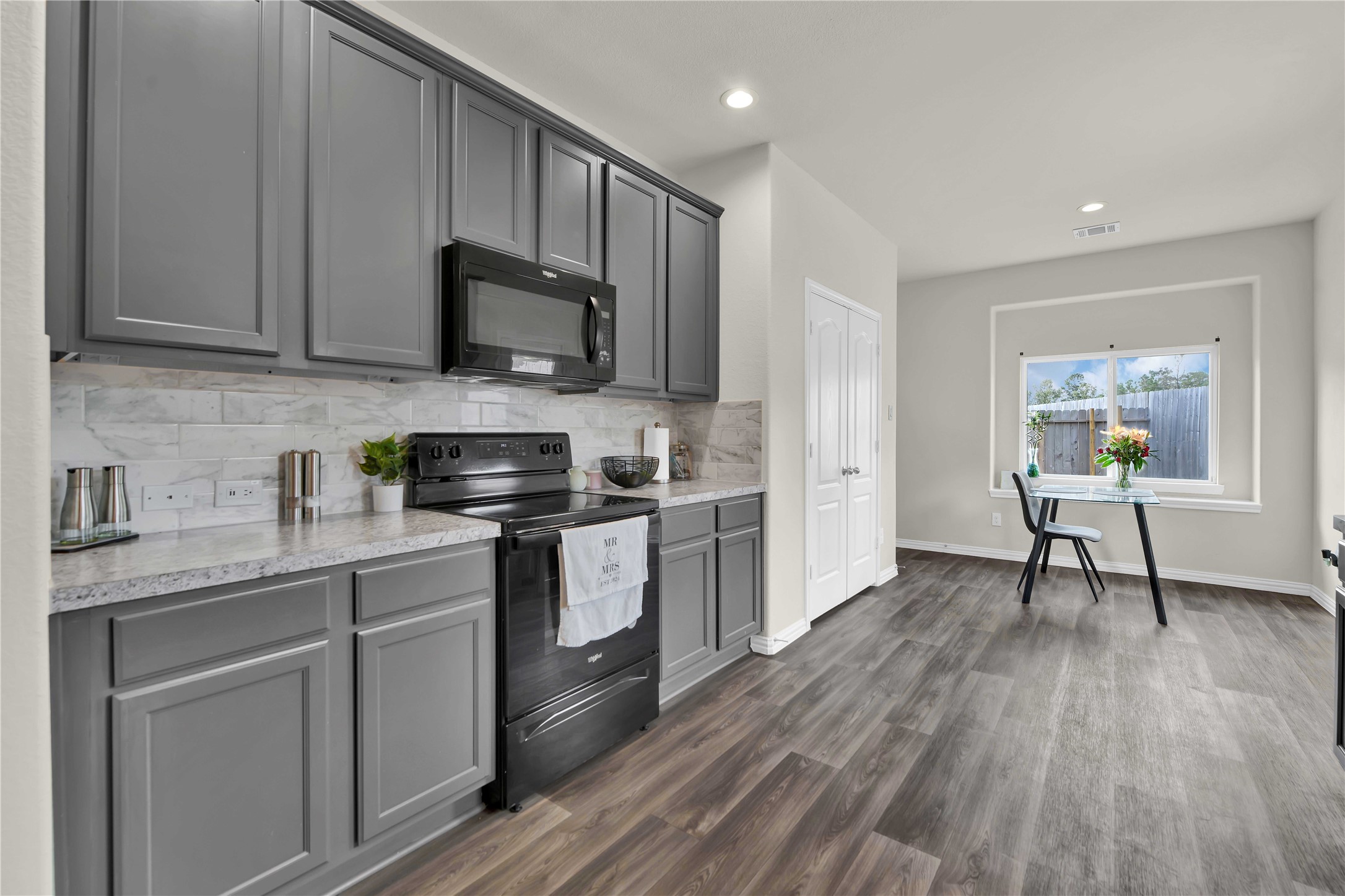 17703 Lion Heart Road Conroe, TX 77306 - Photo 11 of 26 a kitchen with stainless steel appliances granite countertop a stove a sink dishwasher and a microwave oven with wooden floor