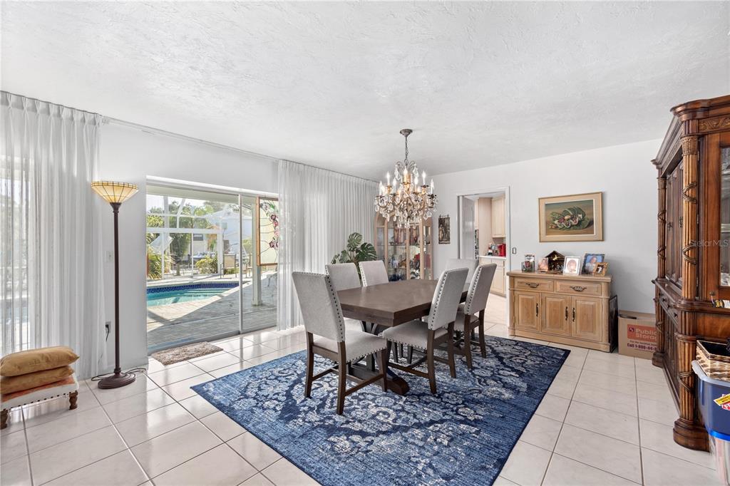 6937 Midnight Pass Road Sarasota, FL 34242 - Photo 7 of 30 a dining room with furniture a rug a potted plant and a chandelier