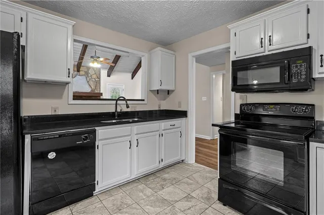 a kitchen with granite countertop white cabinets stainless steel appliances and a sink