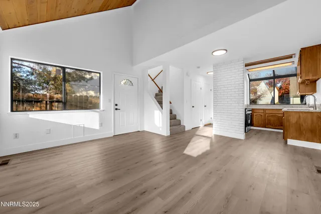 a view of an empty room with a window and wooden floor