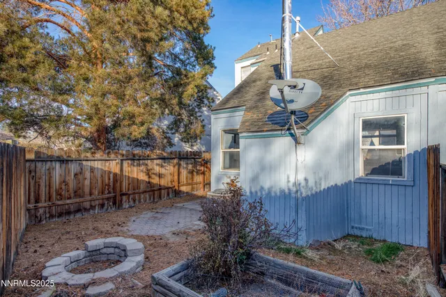 a backyard of a house with chairs plants and wooden fence