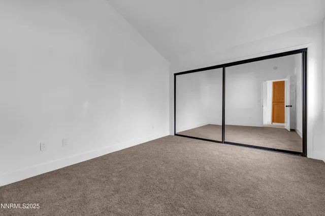 a view of an empty room with closet and a window