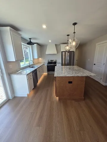 a living room with kitchen island granite countertop wooden floor and stainless steel appliances