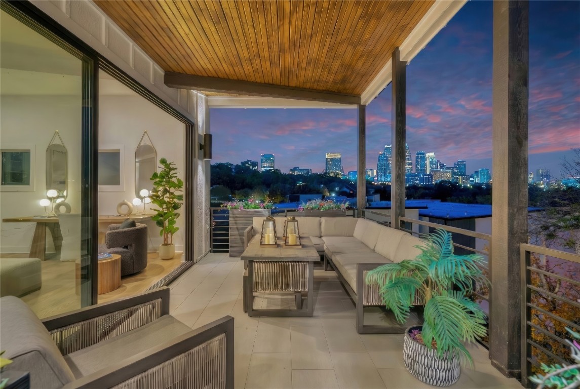 Balcony at dusk featuring an outdoor hangout area, a patio area, and a view of skyline