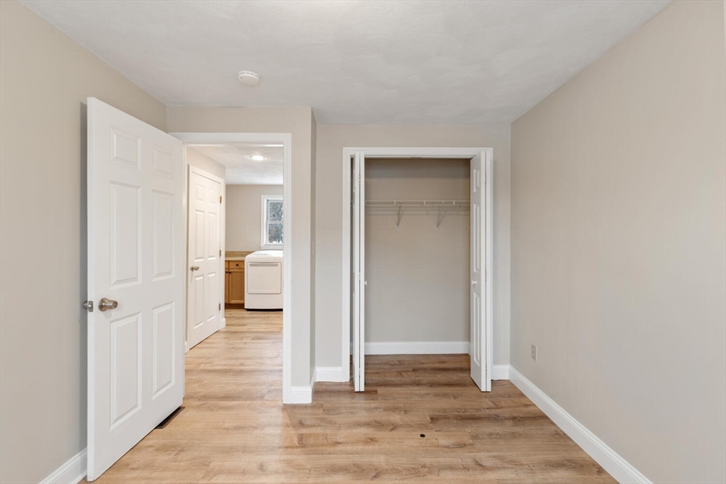 299 Asbury Street Hamilton, MA 01982 - Photo 27 of 37 a view of a hallway with wooden floor and a bathroom