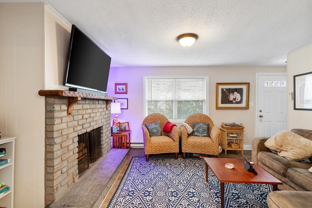 299 Asbury Street Hamilton, MA 01982 - Photo 6 of 37 a living room with furniture a flat screen tv and a fireplace