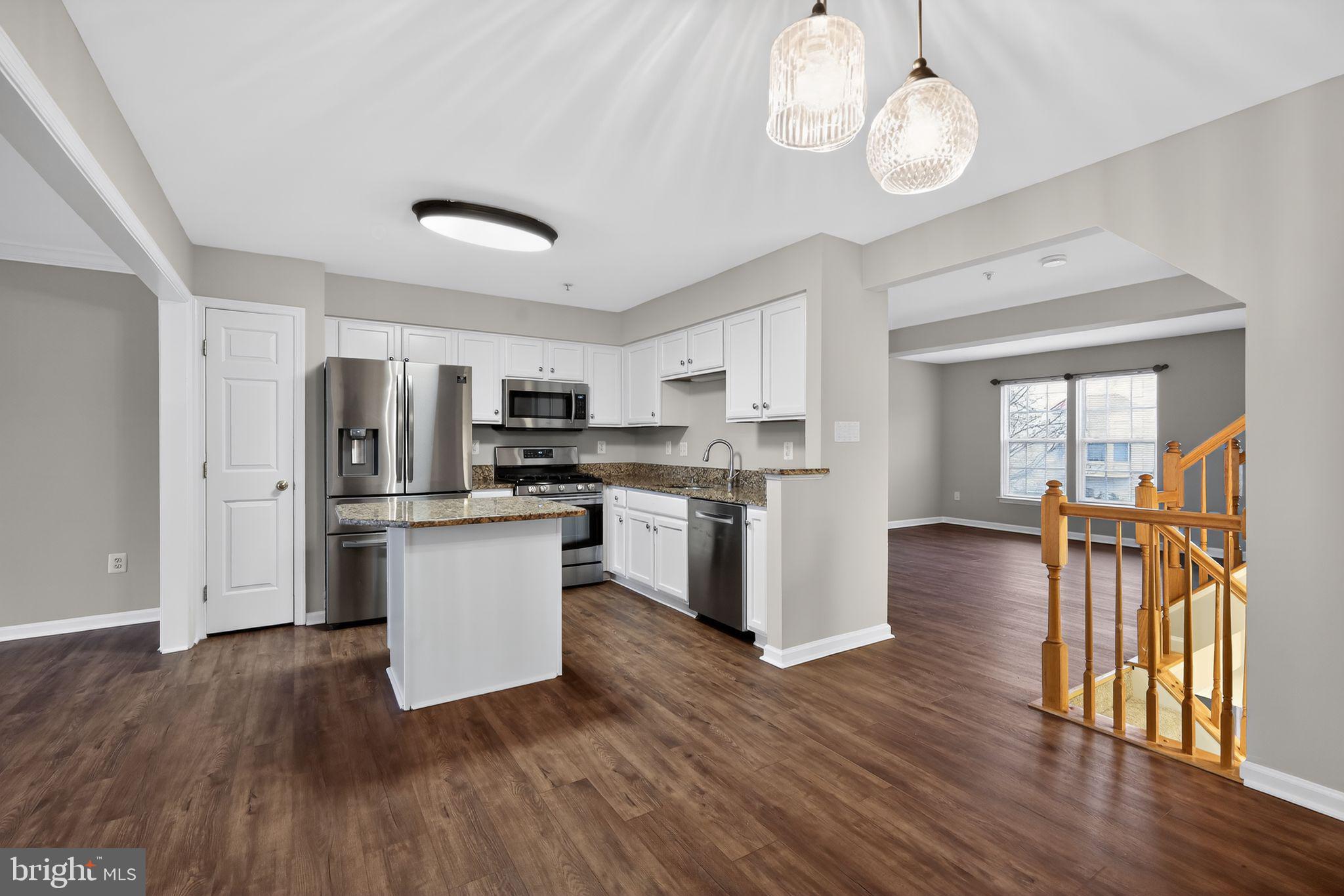 18707 Little Star Lane Germantown, MD 20874 - Photo 5 of 30 a kitchen with stainless steel appliances granite countertop a refrigerator a stove top oven a sink dishwasher and white cabinets with wooden floor