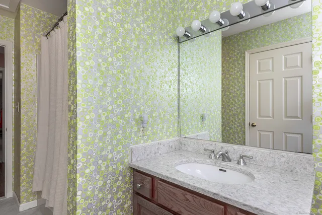 a bathroom with a granite countertop sink a mirror and shower