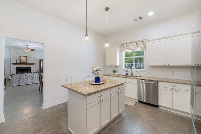 a kitchen with a sink dishwasher a stove and white cabinets with wooden floor
