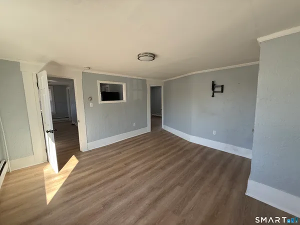 a view of an empty room with wooden floor and a window
