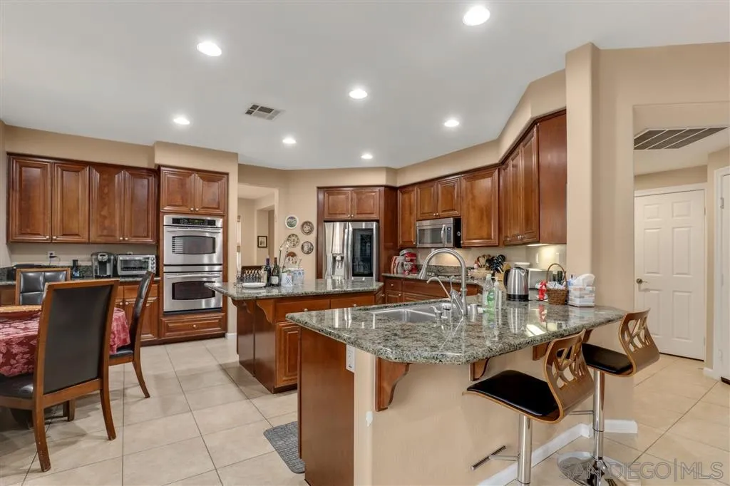 8403 Watson Ranch Road San Diego, CA 92129 - Photo 7 of 25 a kitchen with stainless steel appliances granite countertop table chairs stove and refrigerator