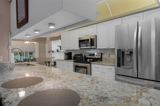 a kitchen with stainless steel appliances granite countertop a stove a refrigerator and a white cabinets