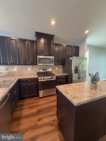 a kitchen with kitchen island granite countertop stainless steel appliances and wooden cabinets