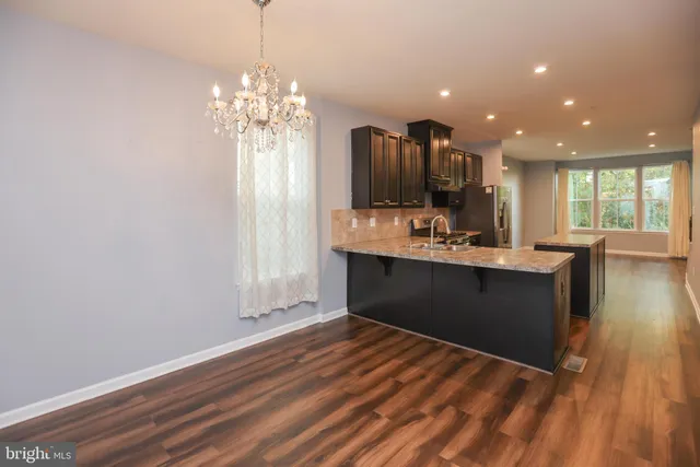 a kitchen with kitchen island granite countertop a sink cabinets and wooden floor