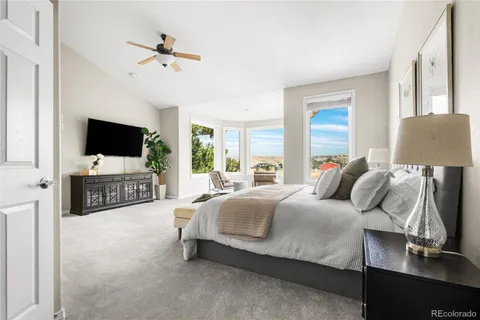 a spacious bedroom with a bed and a flat tv screen on dresser