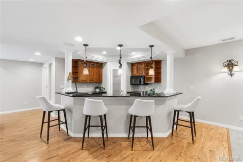 a kitchen with stainless steel appliances kitchen island granite countertop a table chairs sink and cabinets