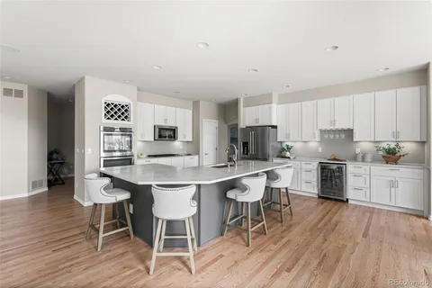 a kitchen with a dining table chairs cabinets and wooden floor
