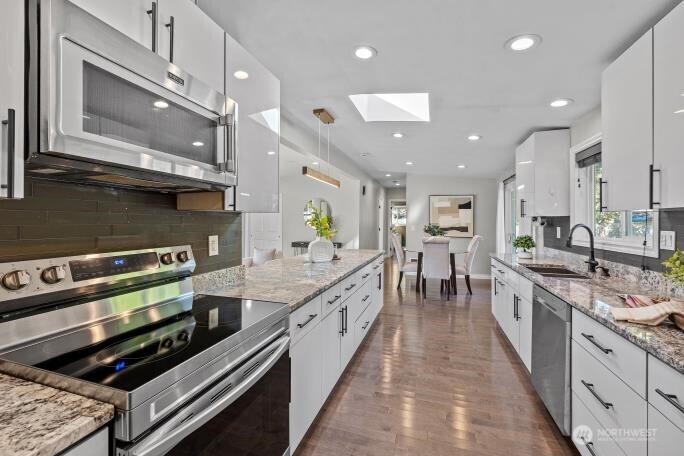 21904 88th Place West Edmonds, WA 98026 - Photo 12 of 40 a large kitchen with stainless steel appliances kitchen island granite countertop a large stove a sink and a microwave