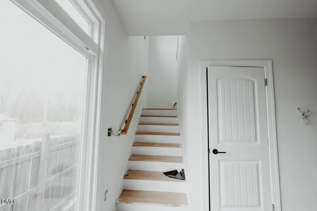 a view of staircase with white walls and white door