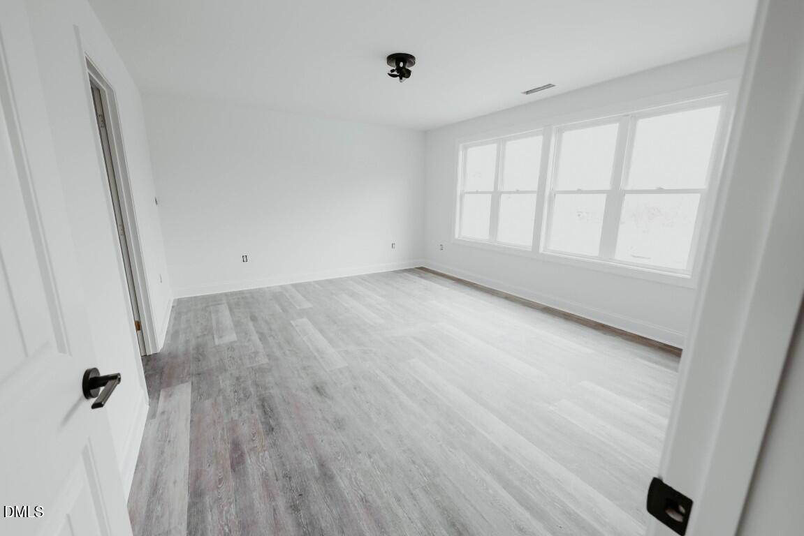 309 East Perry Avenue Wake Forest, NC 27587 - Photo 10 of 24 an empty room with wooden floor and windows