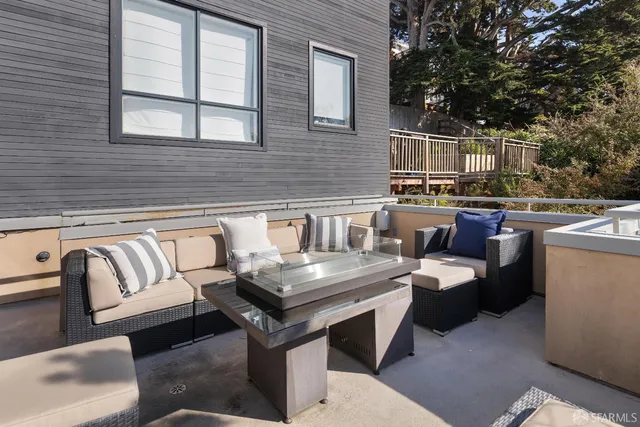 a view of a patio with couches and table and chairs with wooden fence