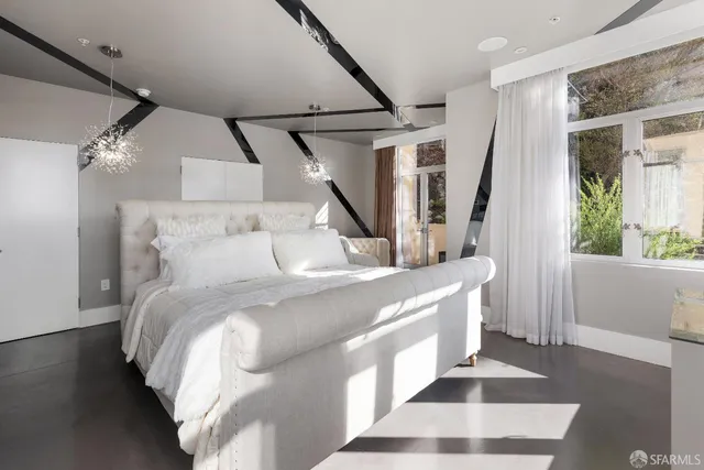 a large white bed sitting in a bedroom next to a window