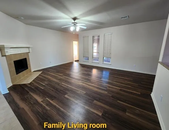 an empty room with a chandelier fan and windows