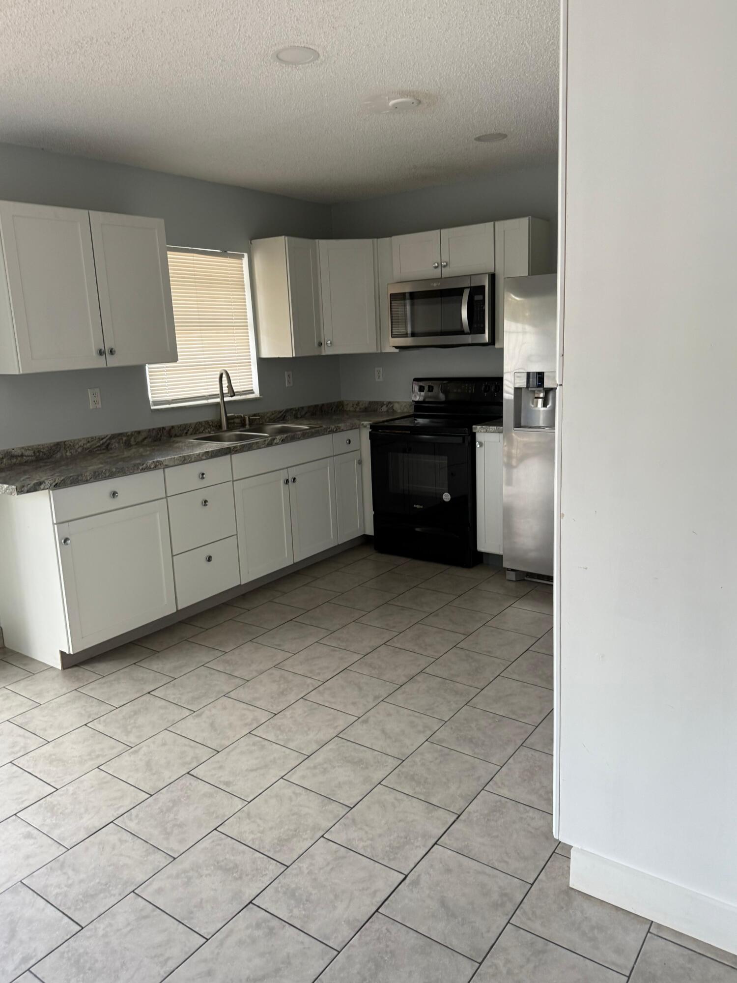 29714 Southwest 158th Place Homestead, FL 33033 - Photo 2 of 3 a large kitchen with granite countertop white cabinets and stainless steel appliances