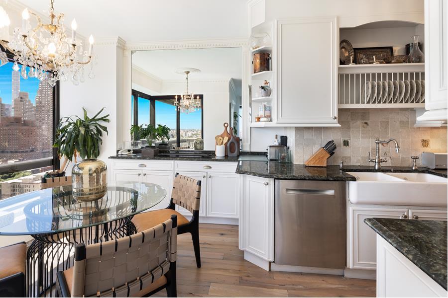 530 East 76th Street, Unit 21HJK Manhattan, NY 10021 - Photo 6 of 21 a kitchen with granite countertop a table chairs stove and cabinets