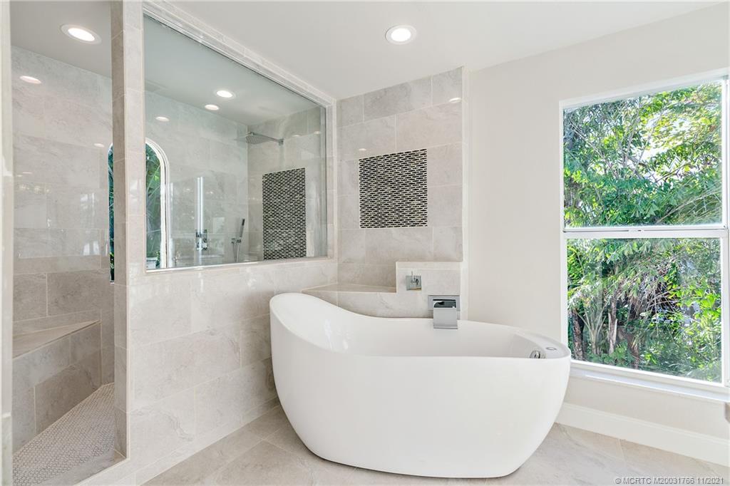 1037 Southeast Riverside Drive Stuart, FL 34996 - Photo 27 of 46 Owners Suite with a Woodbridge Acrylic Free Standing Air and Water Jetted Soaking Tub and Large Custom Walk in Shower, with a one of a kind arched window.