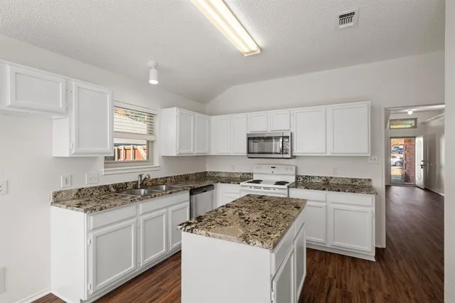 a kitchen with stainless steel appliances granite countertop a stove top oven a sink a counter space and cabinets