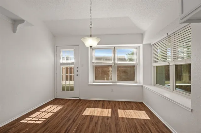 an empty room with wooden floor ceiling fan and windows