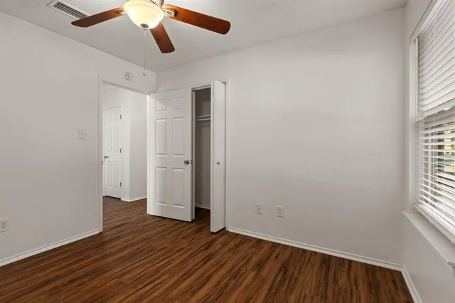 a view of empty room with wooden floor and fan