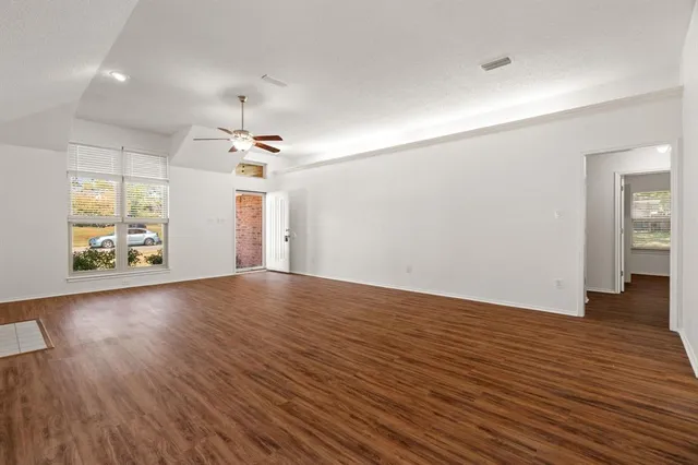 an empty room with wooden floor and windows