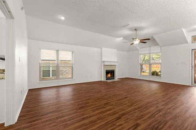 an empty room with wooden floor fireplace and windows