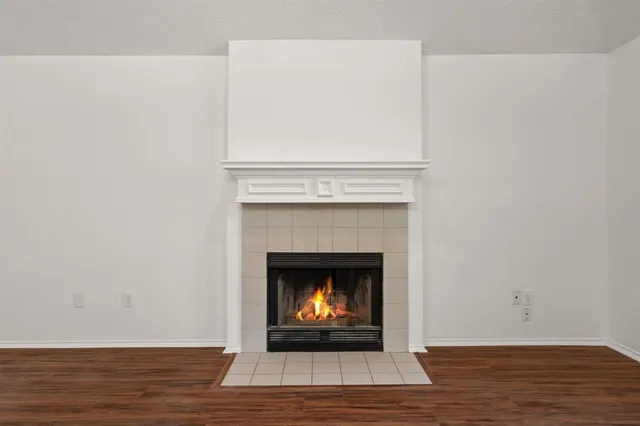 a view of an empty room with wooden floor and a fireplace