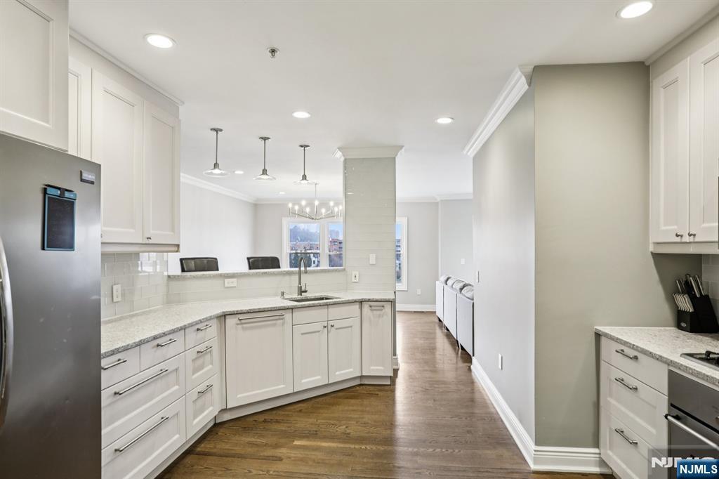 343 The Promenade, Unit 343 Edgewater, NJ 07020 - Photo 11 of 38 a open kitchen with white cabinets and wooden floor