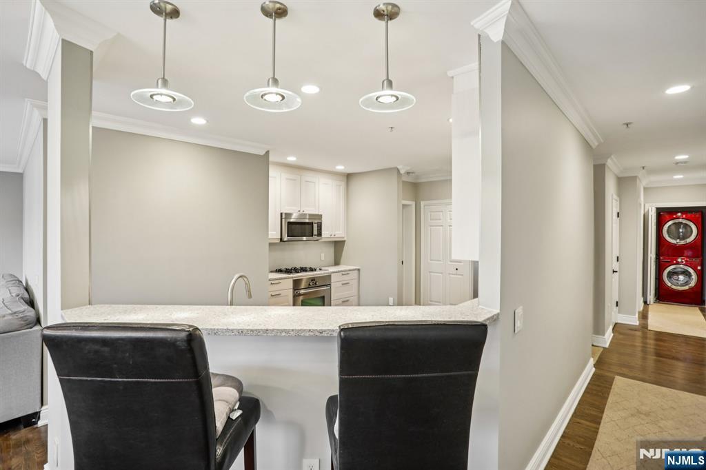 343 The Promenade, Unit 343 Edgewater, NJ 07020 - Photo 15 of 38 a kitchen with kitchen island a stove a sink a refrigerator and a oven with wooden floor