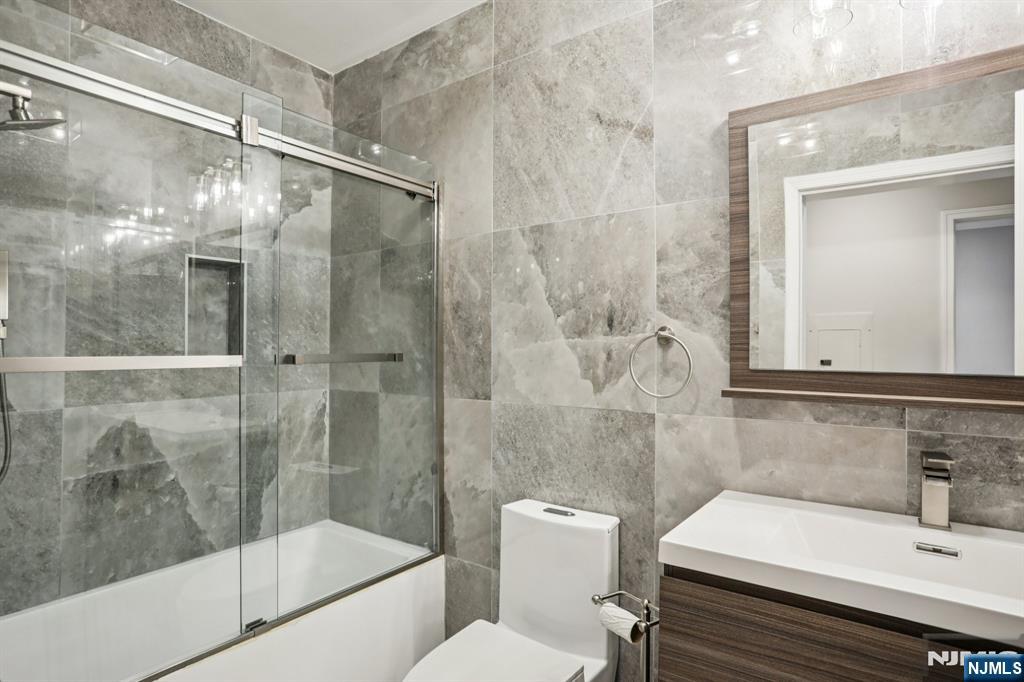 343 The Promenade, Unit 343 Edgewater, NJ 07020 - Photo 18 of 38 a bathroom with a sink and mirror with bathtub