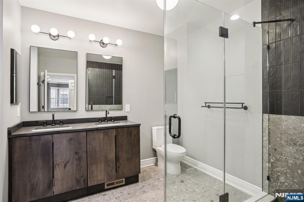 343 The Promenade, Unit 343 Edgewater, NJ 07020 - Photo 24 of 38 a bathroom with a double vanity sink toilet and shower